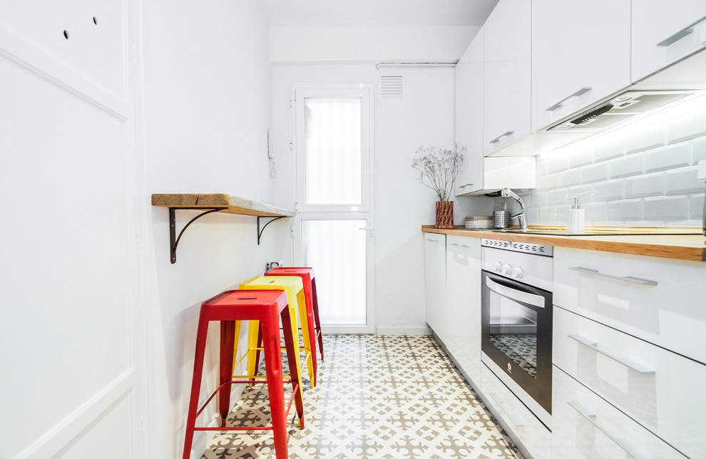 Design ideas for a small scandinavian single-wall separate kitchen in Madrid with a single-bowl sink, white cabinets, wood benchtops, white splashback, subway tile splashback, stainless steel appliances, ceramic floors and no island.