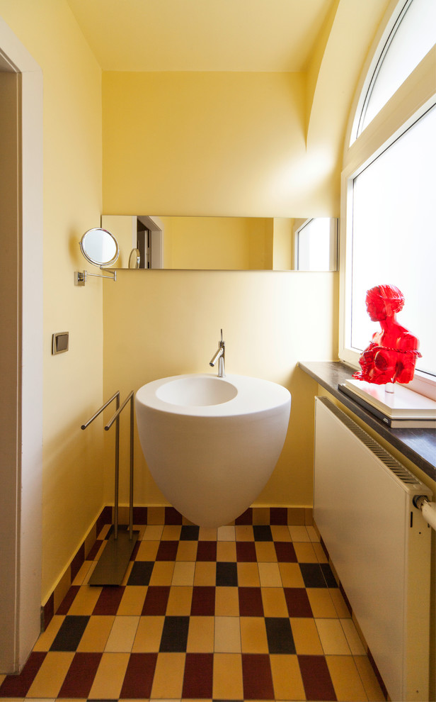 This is an example of a contemporary powder room in Cologne with a wall-mount sink, yellow walls, multi-coloured tile and multi-coloured floor.