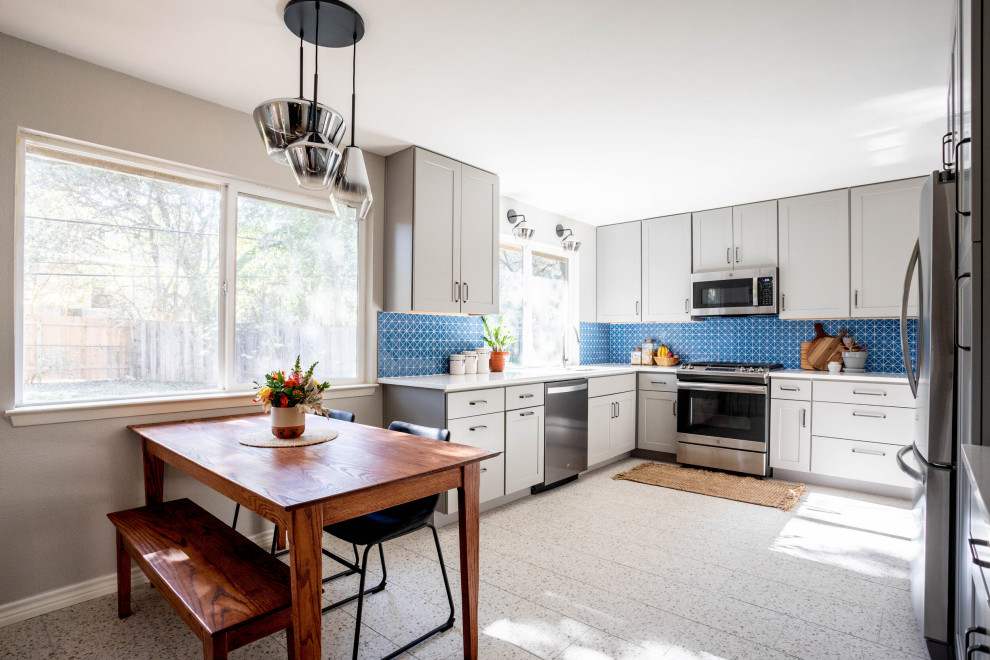 Photo of a mid-sized transitional l-shaped separate kitchen in Austin with an undermount sink, shaker cabinets, grey cabinets, quartz benchtops, blue splashback, ceramic splashback, stainless steel appliances, no island, multi-coloured floor and white benchtop.