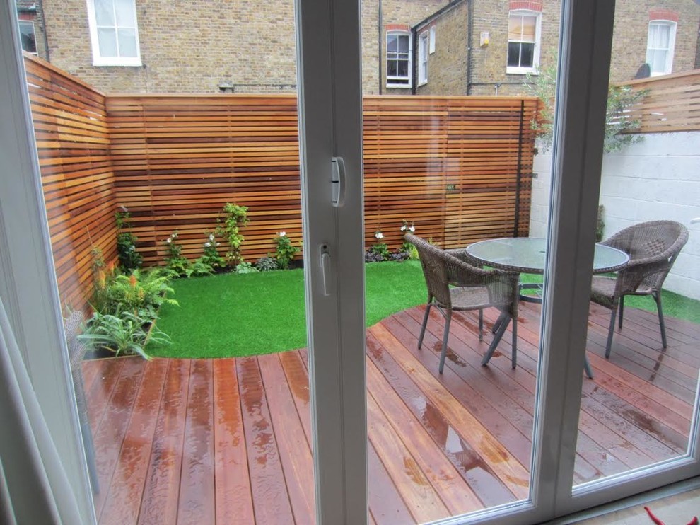 Small modern backyard shaded formal garden in London with decking.