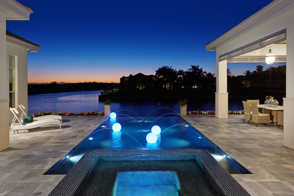 Inspiration for a mid-sized contemporary backyard custom-shaped infinity pool with a hot tub and natural stone pavers.