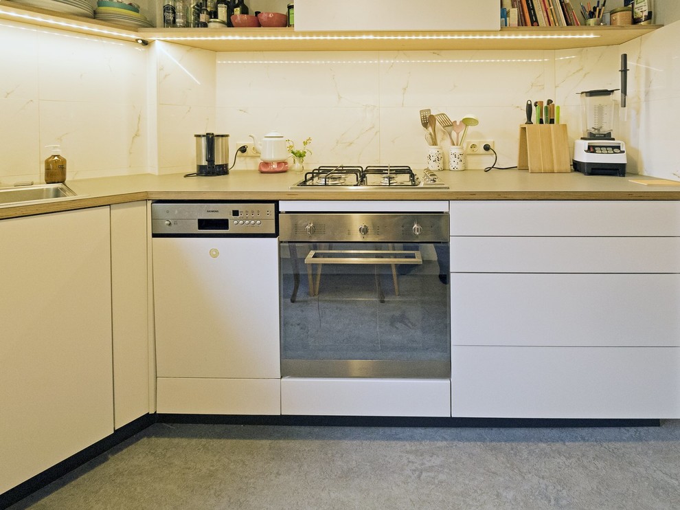 Bild på ett mellanstort industriellt linjärt kök med öppen planlösning, med en nedsänkt diskho, släta luckor, vita skåp, laminatbänkskiva, rostfria vitvaror, linoleumgolv och grått golv