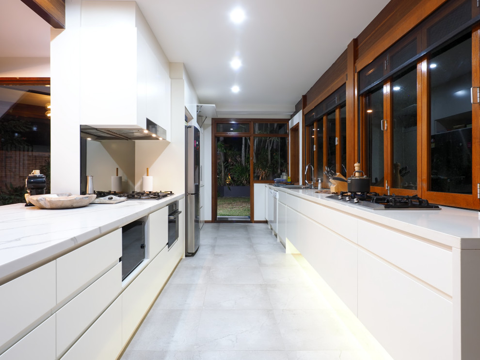 Inspiration for a mid-sized midcentury galley open plan kitchen in Brisbane with a drop-in sink, flat-panel cabinets, white cabinets, marble benchtops, ceramic floors, no island, white floor and white benchtop.
