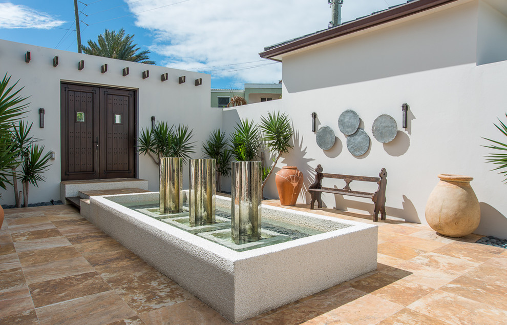 Design ideas for a tropical patio in Other with a water feature.