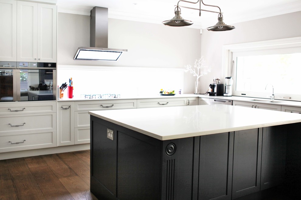 Photo of a large traditional l-shaped eat-in kitchen in Sydney with an undermount sink, shaker cabinets, light wood cabinets, quartz benchtops, white splashback, glass sheet splashback, stainless steel appliances, dark hardwood floors and with island.