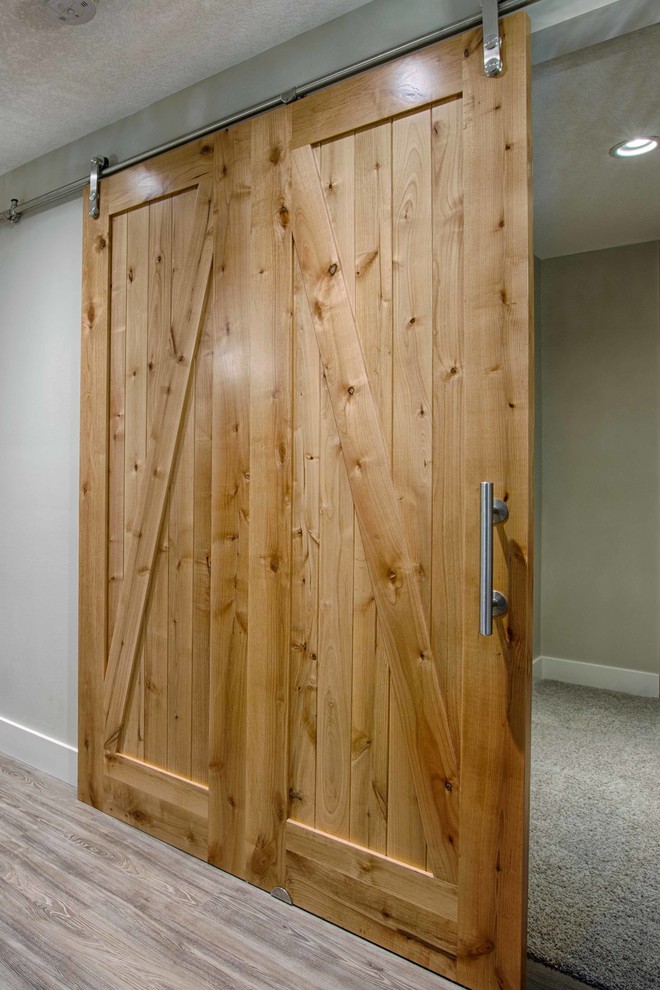 Large mountain style look-out light wood floor basement photo in Calgary with white walls, a standard fireplace and a brick fireplace