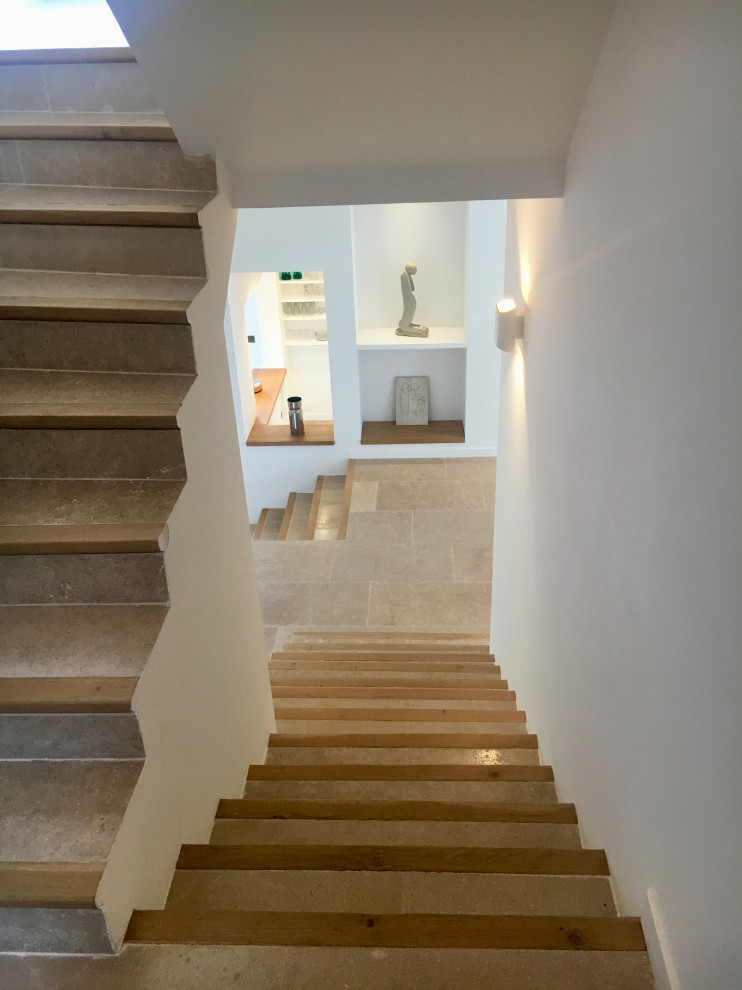 Свежая идея для дизайна: изогнутая лестница среднего размера в современном стиле с ступенями из известняка и подступенками из известняка - отличное фото интерьера