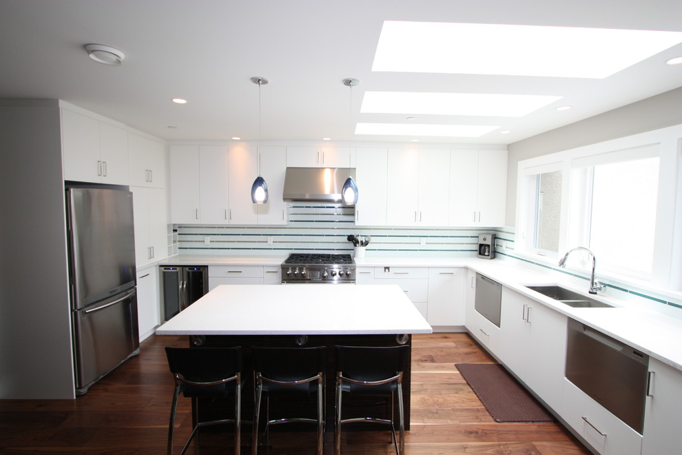 Eat-in kitchen - mid-sized transitional l-shaped medium tone wood floor eat-in kitchen idea in Vancouver with an undermount sink, flat-panel cabinets, white cabinets, quartz countertops, white backsplash, glass tile backsplash, stainless steel appliances and an island