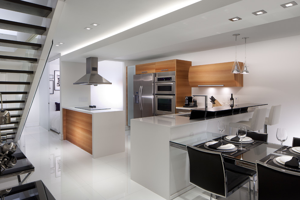 Design ideas for a small modern eat-in kitchen in Miami with light wood cabinets, stainless steel appliances, quartz benchtops, white splashback and multiple islands.