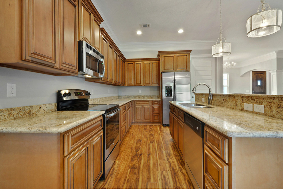Open concept kitchen - large transitional l-shaped medium tone wood floor open concept kitchen idea with an undermount sink, raised-panel cabinets, medium tone wood cabinets, granite countertops, stainless steel appliances and an island