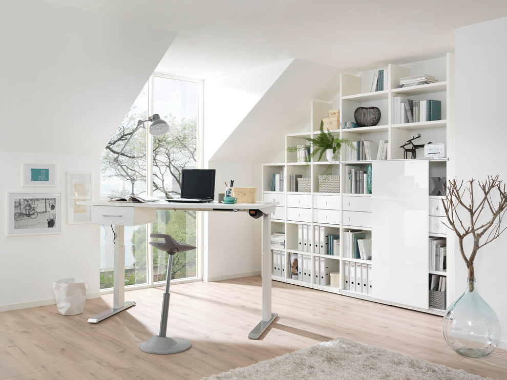 Photo of a mid-sized contemporary study room in Dresden with white walls, light hardwood floors, no fireplace, a freestanding desk and beige floor.
