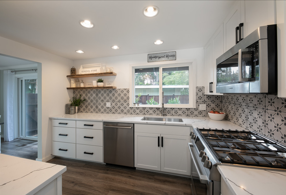 Mid-sized country u-shaped separate kitchen in Seattle with an undermount sink, shaker cabinets, white cabinets, quartz benchtops, grey splashback, ceramic splashback, stainless steel appliances, light hardwood floors, no island, grey floor and white benchtop.