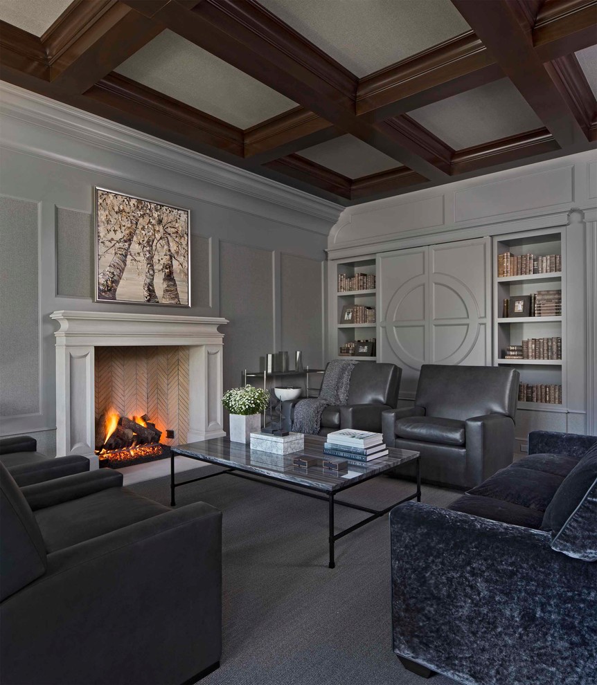 Inspiration for a transitional living room in Detroit with a library, grey walls, carpet, a standard fireplace, a stone fireplace surround, a concealed tv and grey floor.
