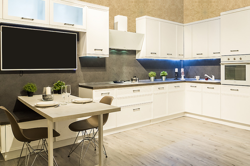 Modelo de cocina comedor tradicional renovada con electrodomésticos blancos, suelo de madera en tonos medios y suelo beige