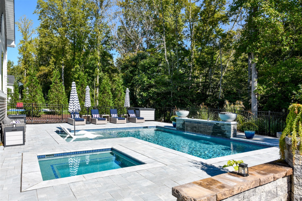 Foto de piscina con fuente actual de tamaño medio en forma de L en patio trasero con adoquines de hormigón