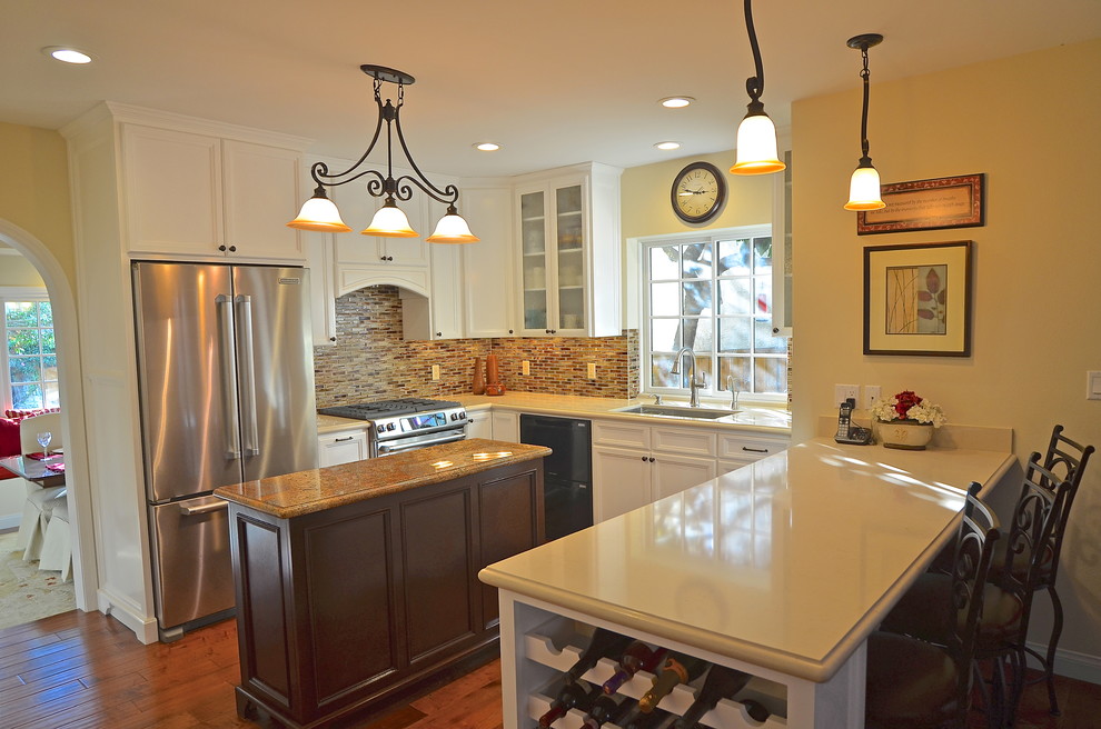 Mid-sized traditional u-shaped separate kitchen in Los Angeles with an undermount sink, shaker cabinets, white cabinets, limestone benchtops, multi-coloured splashback, subway tile splashback, stainless steel appliances, medium hardwood floors and with island.