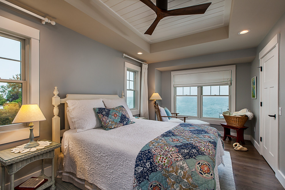 Example of a mid-sized beach style master dark wood floor, brown floor, shiplap ceiling and tray ceiling bedroom design in Grand Rapids with no fireplace and gray walls