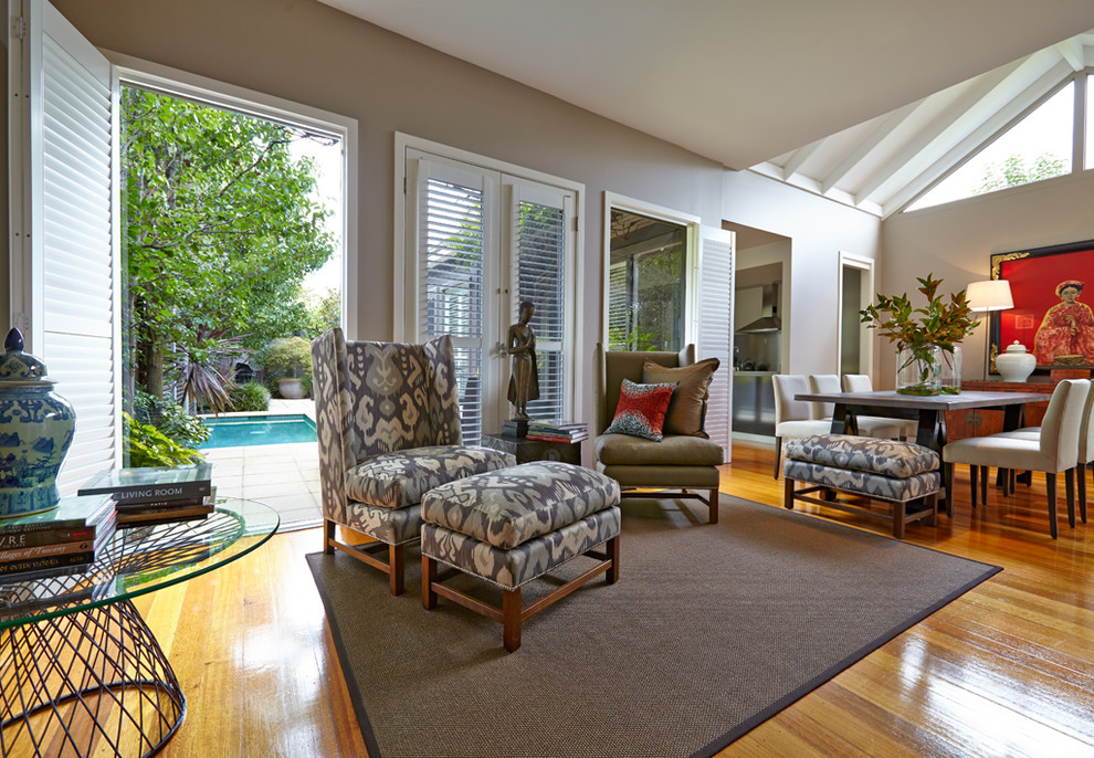 This is an example of a mid-sized contemporary formal open concept living room in Melbourne with medium hardwood floors, a standard fireplace, beige walls, a wood fireplace surround and no tv.