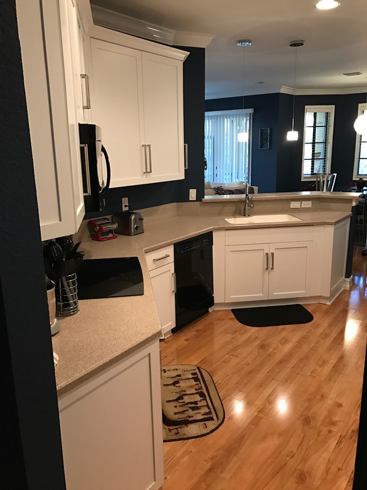 Inspiration for a small transitional galley bamboo floor eat-in kitchen remodel in Miami with an undermount sink, shaker cabinets, white cabinets, solid surface countertops and stainless steel appliances