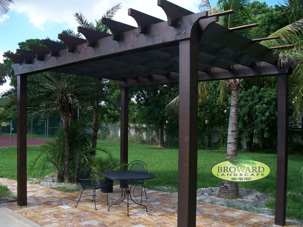 Photo of a tropical backyard deck in Miami with a pergola.