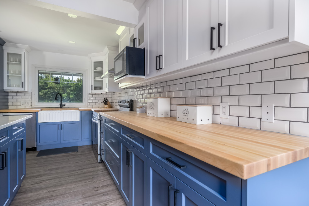 Example of a transitional kitchen design in Edmonton with shaker cabinets, blue cabinets, quartzite countertops, subway tile backsplash, stainless steel appliances, an island and white countertops