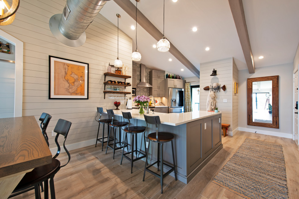 Design ideas for a small rustic u-shaped open plan kitchen in Tampa with a belfast sink, beaded cabinets, grey cabinets, engineered stone countertops, blue splashback, mosaic tiled splashback, stainless steel appliances, light hardwood flooring, an island, brown floors, white worktops and exposed beams.