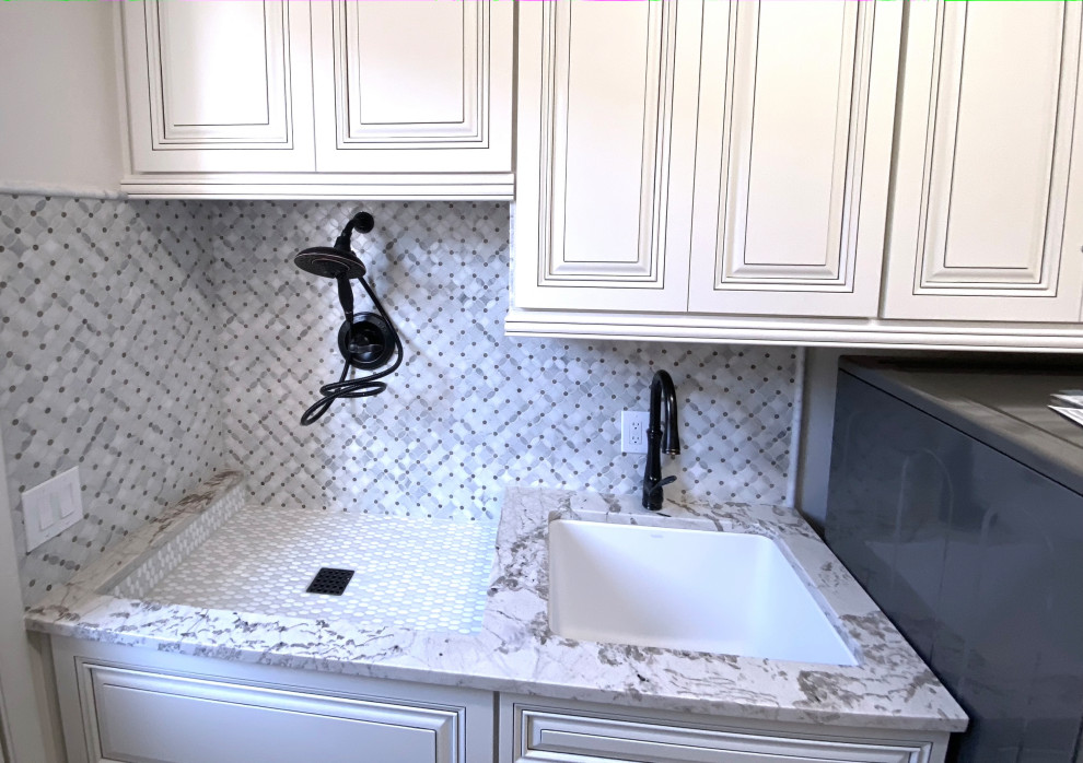This is an example of a large single-wall utility room in Phoenix with an undermount sink, raised-panel cabinets, white cabinets, quartzite benchtops, white walls, travertine floors, a side-by-side washer and dryer, beige floor and white benchtop.