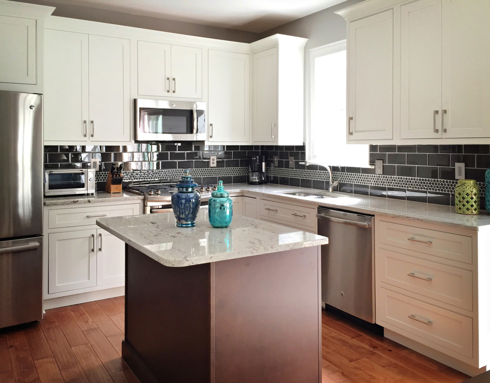 Mid-sized transitional l-shaped eat-in kitchen in Philadelphia with an undermount sink, beaded inset cabinets, white cabinets, granite benchtops, grey splashback, glass tile splashback, stainless steel appliances, medium hardwood floors and with island.