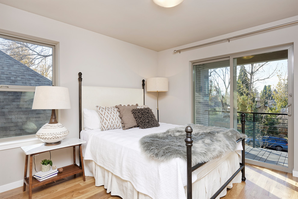 Design ideas for a transitional guest bedroom in Denver with white walls, light hardwood floors and brown floor.