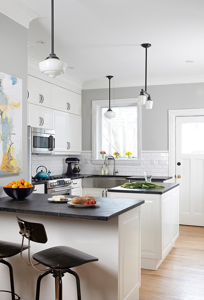 Transitional u-shaped kitchen in Toronto with a farmhouse sink, raised-panel cabinets, white cabinets, white splashback, subway tile splashback and stainless steel appliances.