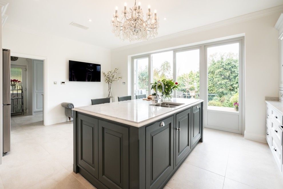 This is an example of a large traditional l-shaped kitchen in Essex with an undermount sink, raised-panel cabinets, grey cabinets, quartzite benchtops, white splashback, stainless steel appliances, porcelain floors, with island, beige floor and white benchtop.