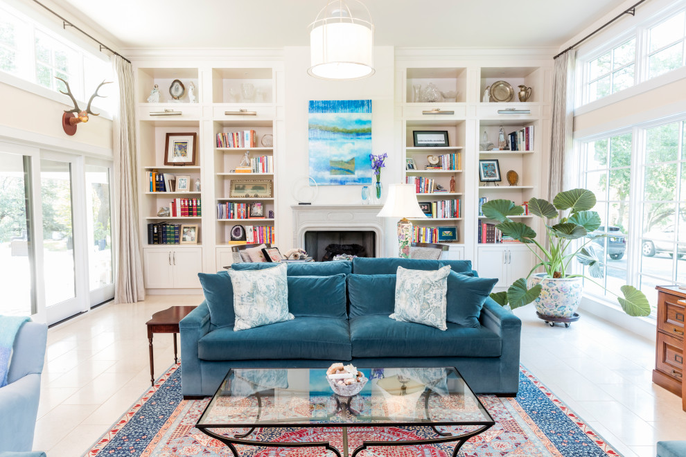 Источник вдохновения для домашнего уюта: большая открытая гостиная комната в классическом стиле с белыми стенами, полом из известняка, стандартным камином, фасадом камина из бетона, телевизором на стене, белым полом и синим диваном