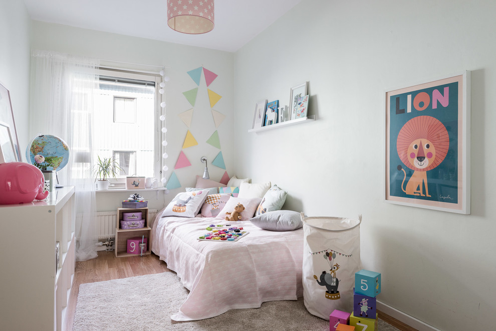 Design ideas for a mid-sized scandinavian kids' room for girls in Gothenburg with white walls and light hardwood floors.