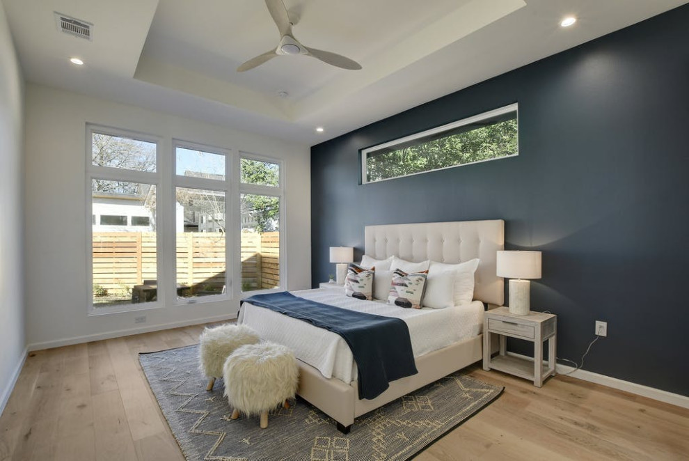 Midcentury master bedroom in Austin with medium hardwood floors and recessed.