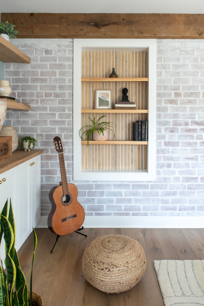 Inspiration pour une salle de séjour traditionnelle de taille moyenne avec un mur multicolore, un sol en bois brun, une cheminée standard, un manteau de cheminée en plâtre, un téléviseur encastré, un sol marron et un mur en parement de brique.