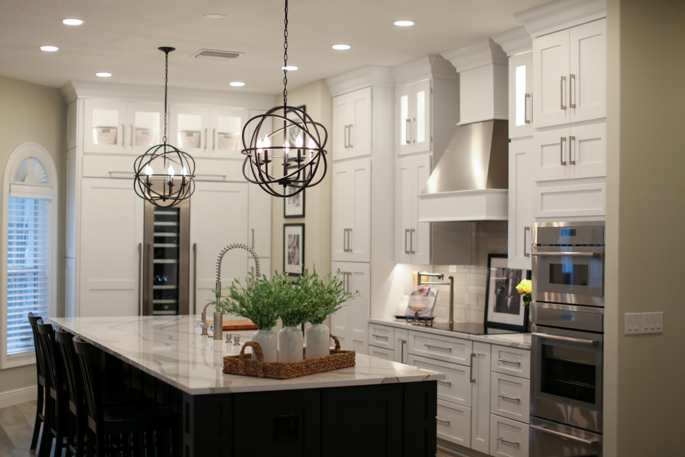Design ideas for a large transitional galley eat-in kitchen in Orlando with a farmhouse sink, shaker cabinets, white cabinets, quartz benchtops, grey splashback, ceramic splashback, panelled appliances, vinyl floors, with island, grey floor and white benchtop.