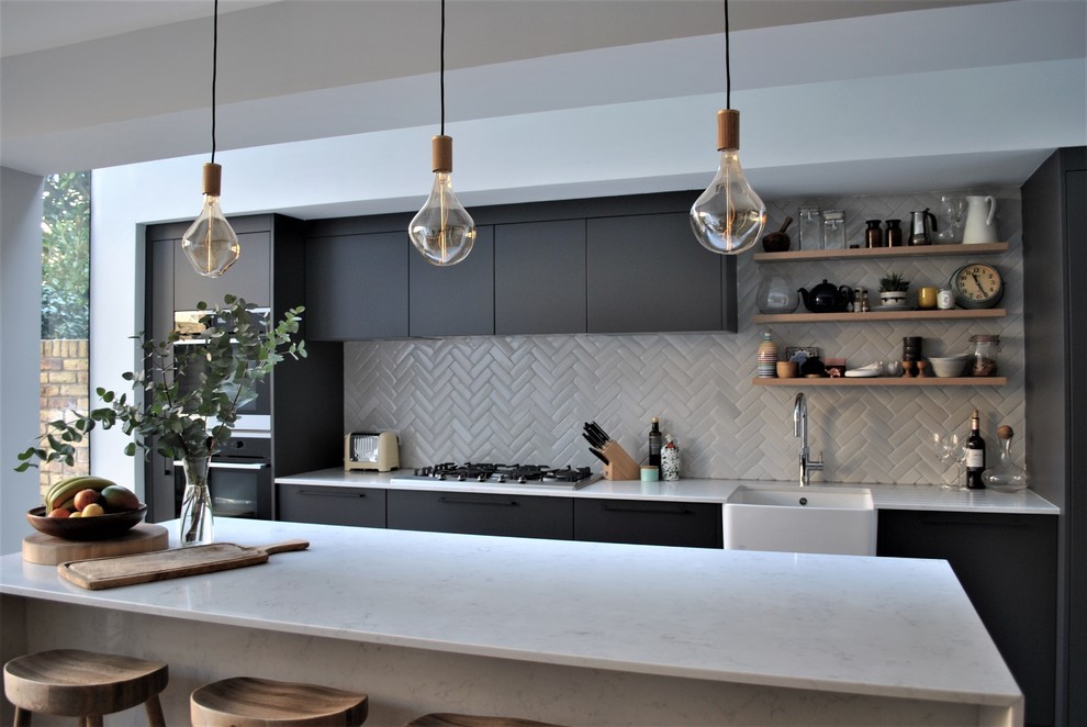 This is an example of a contemporary eat-in kitchen in London with a farmhouse sink, flat-panel cabinets, grey cabinets, quartzite benchtops, white splashback, subway tile splashback, ceramic floors and multi-coloured floor.