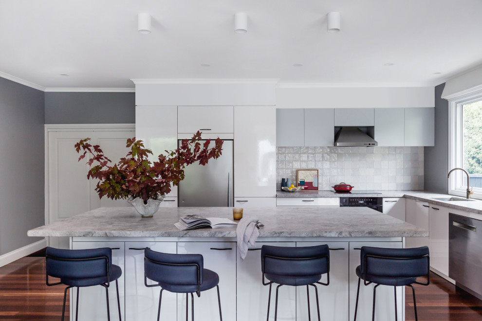 Große Moderne Küche in L-Form mit Unterbauwaschbecken, weißen Schränken, Marmor-Arbeitsplatte, Küchenrückwand in Grau, Rückwand aus Terrakottafliesen, braunem Holzboden, Kücheninsel und grauer Arbeitsplatte in Melbourne
