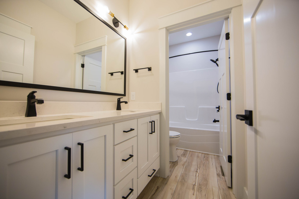 Bathroom - mid-sized traditional kids' light wood floor, brown floor and single-sink bathroom idea in Indianapolis with recessed-panel cabinets, white cabinets, a two-piece toilet, beige walls, an undermount sink, quartzite countertops, white countertops and a freestanding vanity