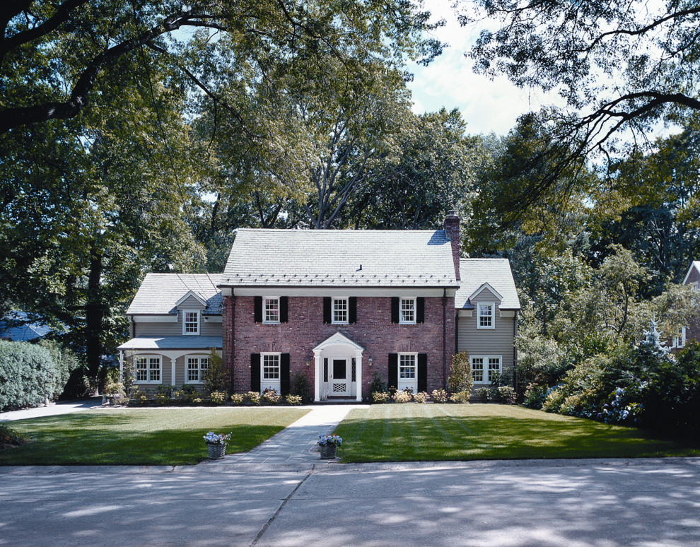 Photo of a large traditional two-storey brick red house exterior in New York with a gable roof and a shingle roof.