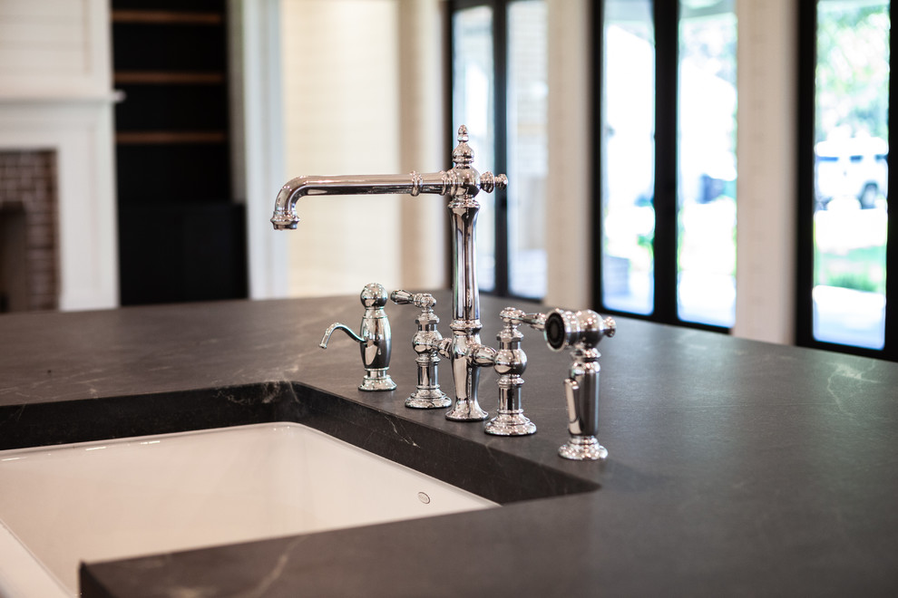Example of a transitional home design design with a farmhouse sink, recessed-panel cabinets, black cabinets, soapstone countertops and black countertops