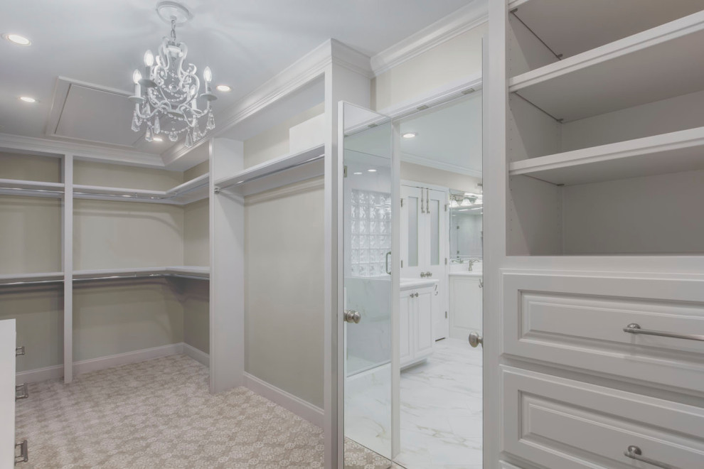Photo of a large transitional walk-in wardrobe in Other with raised-panel cabinets, white cabinets, carpet and beige floor.