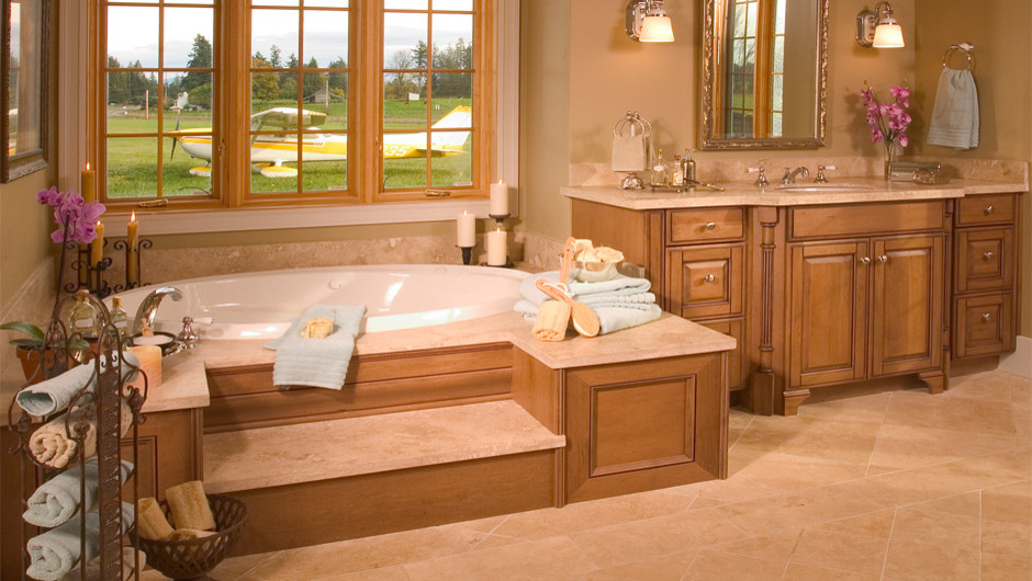 Photo of a traditional bathroom in Seattle with an undermount sink, raised-panel cabinets, medium wood cabinets, marble benchtops, a drop-in tub, an open shower, a one-piece toilet, beige tile and stone tile.