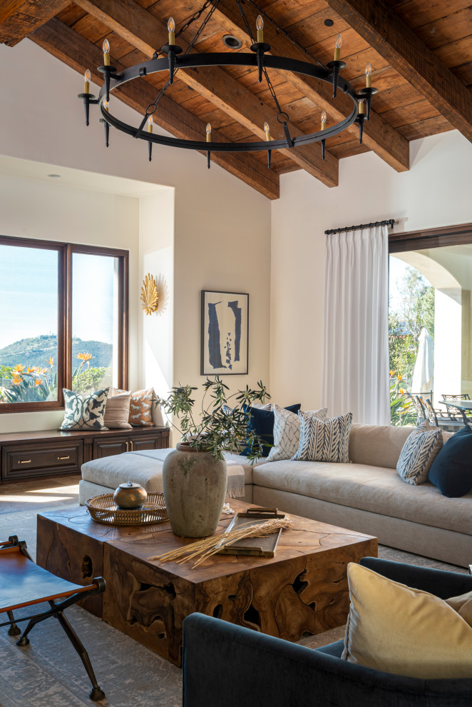 Living room - large mediterranean medium tone wood floor, brown floor, exposed beam, vaulted ceiling and wood ceiling living room idea in San Diego with white walls