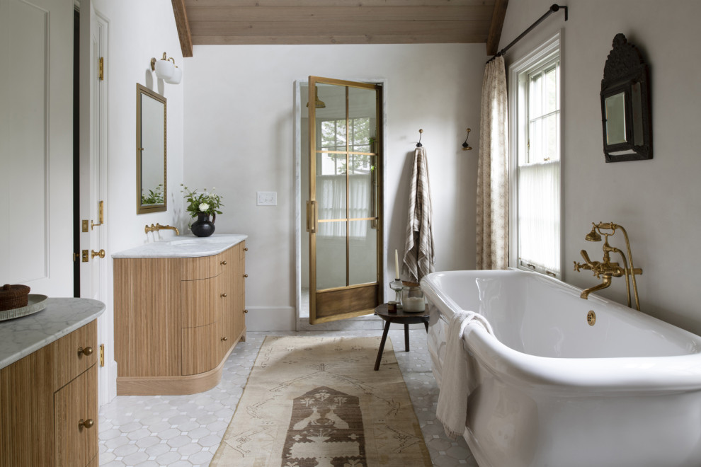 Badezimmer En Suite mit hellen Holzschränken, freistehender Badewanne, weißer Waschtischplatte, Doppelwaschbecken, Duschnische, grauem Boden und Falttür-Duschabtrennung in Minneapolis