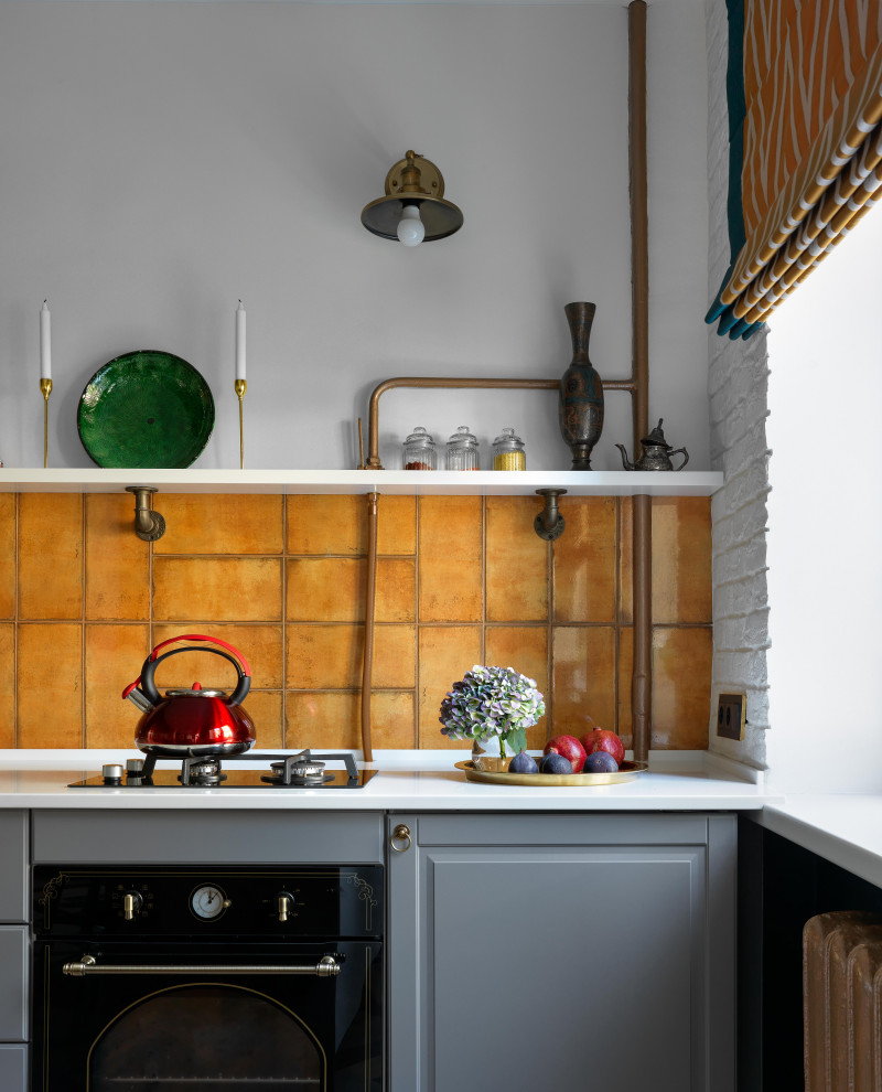Пример оригинального дизайна: маленькая прямая кухня в современном стиле с обеденным столом, врезной мойкой, фасадами в стиле шейкер, серыми фасадами, столешницей из акрилового камня, оранжевым фартуком, фартуком из керамической плитки, черной техникой, полом из керамической плитки, разноцветным полом, белой столешницей и красивой плиткой без острова для на участке и в саду