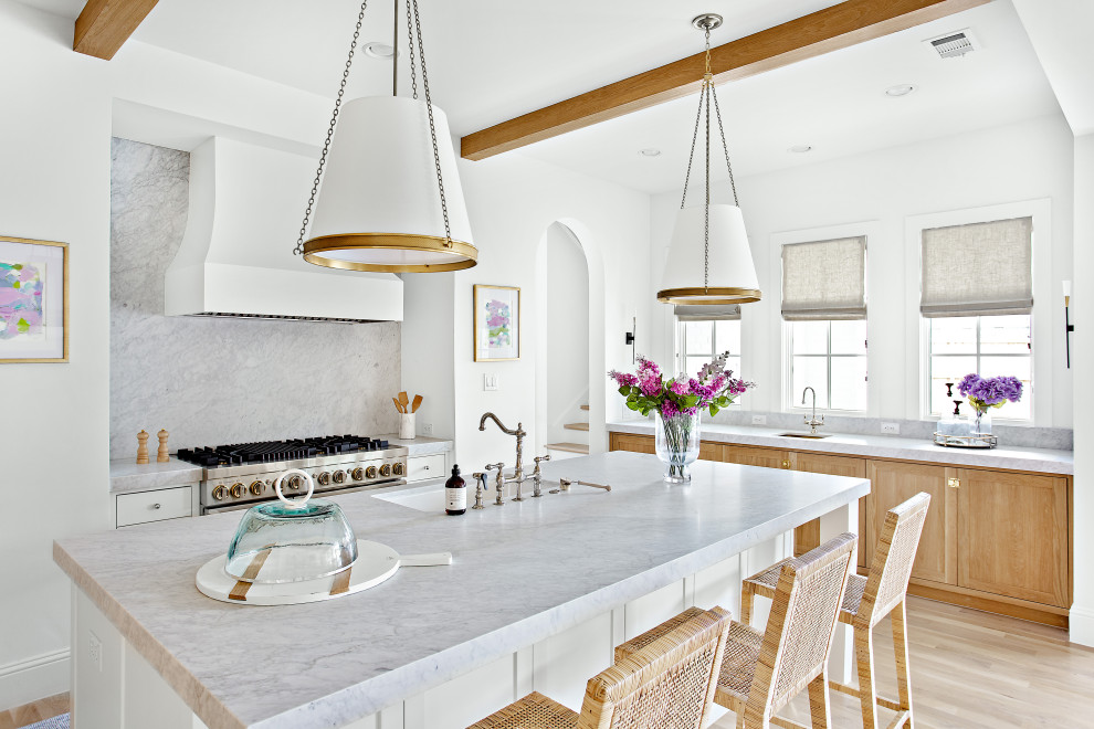 This is an example of a large transitional l-shaped open plan kitchen in Dallas with an undermount sink, shaker cabinets, white cabinets, marble benchtops, white splashback, marble splashback, panelled appliances, light hardwood floors, with island, brown floor, white benchtop and exposed beam.
