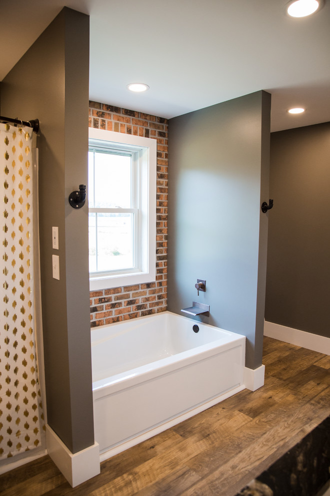 Inspiration for a mid-sized country master bathroom in Other with recessed-panel cabinets, white cabinets, an alcove tub, a shower/bathtub combo, a one-piece toilet, grey walls, vinyl floors, an undermount sink, granite benchtops, brown floor, a shower curtain and black benchtops.