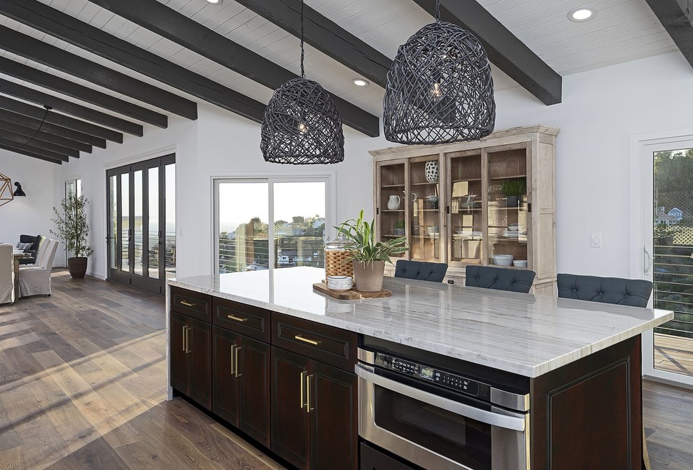 Inspiration for a large country eat-in kitchen in Houston with raised-panel cabinets, dark wood cabinets, granite benchtops, light hardwood floors, with island, brown floor and grey benchtop.