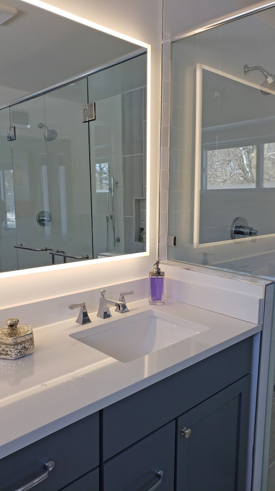 Inspiration for a large transitional master gray tile and porcelain tile porcelain tile, gray floor and double-sink walk-in shower remodel with shaker cabinets, gray cabinets, a two-piece toilet, white walls, an undermount sink, quartz countertops, a hinged shower door, white countertops, a niche and a built-in vanity